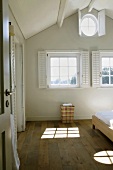 Ruhiger Schlafraum mit drei Fenstern und Fensterläden unter dem ausgebauten Dach