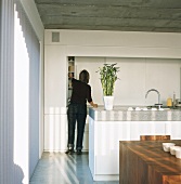 Woman in kitchen in front of wall of fitted cupboards