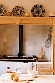Wood oven in kitchen below china plates on wooden shelf