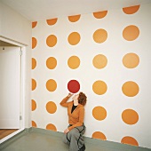 Woman kneeling in front of polka-dot wallpaper