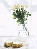 Sliced nut cake with a bunch of white roses