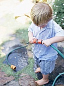 Little boy playing with garden hose