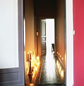 Blick durch geöffnete Türen in Flur mit brennende Kerzen auf dem Boden