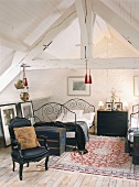 Ein Schlafzimmer im Dachgeschoss mit weißer Holzbalkendecke, französischem Bett und barockem Sessel