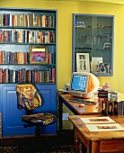 Arbeitszimmer in leuchtenden Farben mit Glasvitrine, Bücherregal und Schreibtisch