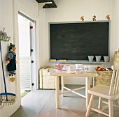 Weiß vertäfeltes Spielzimmer mit Teegedeck, Schultafel und Spielsachen