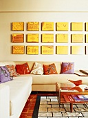 Ecksofa mit bunten Kissen, an der Wand eine gelbe Bilderserie