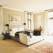 Helles Schlafzimmer mit einem weißen Sofa vor dem großen Doppelbett