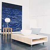 Designercouchtisch auf Rollen und blaues Gemälde in einem weissen Raum