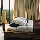 Doppelbett mit integrierten Nachtleuchten in einem Raum mit Dielenboden und verglasten Seiten