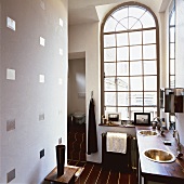 Badezimmer mit Waschtisch und Boden aus Holz in einem hohen Raum mit großem Rundbogenfenster