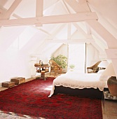 Schlafraum im ausgebauten Dachgeschoss mit Balkontür und großem Teppich