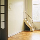 Leerer Raum mit einer Holztreppe und großem Fenster
