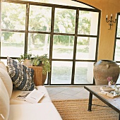 Wohnraumausschnitt mit breiten Sprossenfenstern aus Metall und Blick auf den Garten