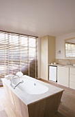 Freistehende Badewanne mit Holzvertäfelung in einem großzügigen Badezimmer mit raumhohen Fenstern