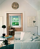 Die geöffneten Flügeltüren eröffnen den Blick vom Wohnzimmer mit gemütlichem Sofa in einen kleinen Nebenraum mit klassischem Schiebefenster