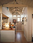 Der Blick durch das romantische Holzhaus fluchtet über die offene Küche hinweg auf einen Treppenaufgang