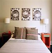Kastenförmige Nachttische in Rot und eine Blütenfotoserie verschaffen dem modernen Schlafzimmer das gewisse Etwas