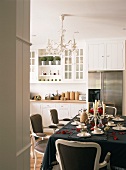 Ein festlich gedeckter Esstisch mit Barockstühlen in einer weissen Landhausküche