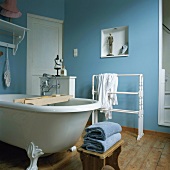 Eine Clawfoot Badewanne und ein gedrechselter Handtuchhalter in einem blauen Badezimmer