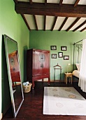 Eine rustikale Holzbalkendecke und ein roter Antikschrank aus Asien verleihen dem gemütlichen Schlafzimmer einen internationalen Touch