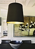 Ein schwarzer Lampenschirm über dem eleganten Essplatz kontrastiert den prunkvollen Wohnraum mit aufwendiger Stuckdecke