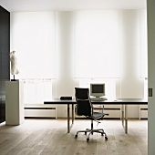 Designerschreibtisch und Torso im modernen Arbeitszimmer mit Holzboden und großer Fensterfront