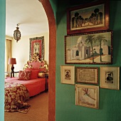 Blick vorbei an einer grünen Bilderwand in ein Schlafzimmer mit prunkvollem Bett