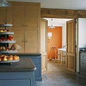 Obstetagère in einer Vintageküche mit Blick durch geöfnete Flügeltüren ins moderne Arbeitszimmer