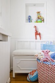 Farbenfrohes Spielzeug und weiße Sitzbank in einer Zimmerecke mit Wandnische