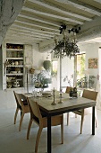 Moderne Holzstühle am gedeckten Esstisch in romantischem Landhausambiente