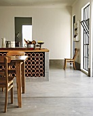 Küchentheke mit Weinregal in einem offenen Wohnraum mit Betonboden und Biedermeierstühlen