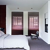 Abgedunkelter Schlafraum mit großem Doppelbett und grauem Teppichboden