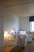 Weisses Babybett in Kinderzimmer mit heller Holzdecke