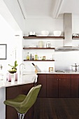 Moderne Küche mit glänzend weisser Theke und grünem Drehstuhl mit Lederbezug