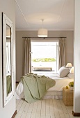 Schlafzimmer mit weiss lackiertem Holzdielenboden und mit direktem Blick auf die Terrasse