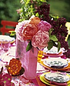 Vase of peonies and lilac on laid table