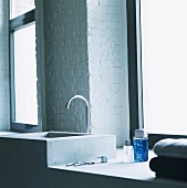 Badezimmerausschnitt mit weiss getünchter Ziegelwand und modernem Waschtisch