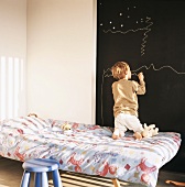 Kinderzimmer mit großer Wandtafel und zeichnendem Kind