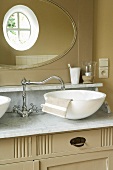 Waschtisch mit Waschschale auf Marmorplatte, nostalgischer Armatur & ovalem Wandspiegel