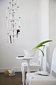 Wohnraum mit mehrarmigem, hängendem Kerzenleuchter & weißem Beistelltisch zwischen Stühlen