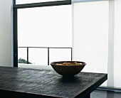 Obstschale auf länglichem schwarzem Tisch vor Balkontür