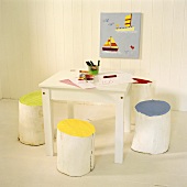 Weisser Kindertisch mit selbstgemachten, bemalten Hockern aus Baumstämmen