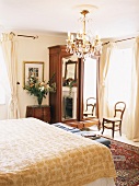 Schlafzimmer mit Doppelbett, antikem Holzschrank & Kronleuchter