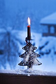 Christmas candle on snow-covered window sill