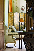 Blick durch geöffnete Tür in Zimmer mit Chaiselongue, Paravent & antikem Polsterstuhl im Schloss La Verrerie (Frankreich)