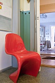 Ein roter, 70er Jahre Panton-Stuhl auf dem Gang
