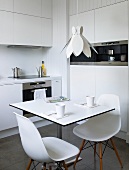 A kitchen with white table and chairs