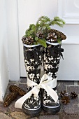 Rubber boots filled with spruce twigs and cones