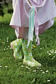 A girl wearing brightly coloured wellie boots in a field